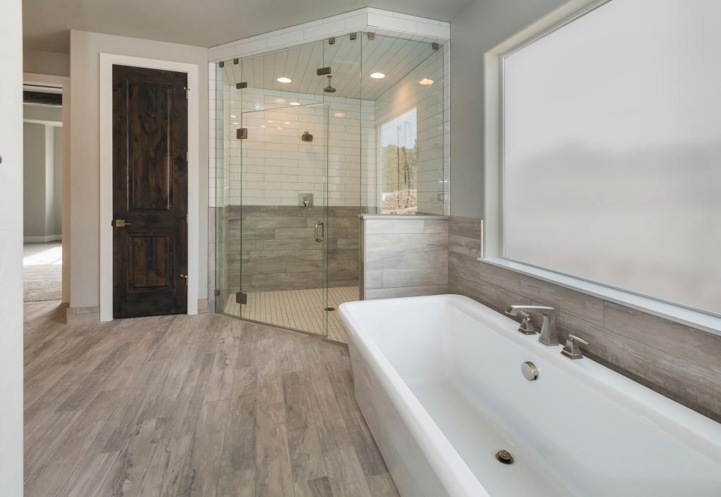 A bathroom in Toronto featuring a glass shower door and wooden floors.