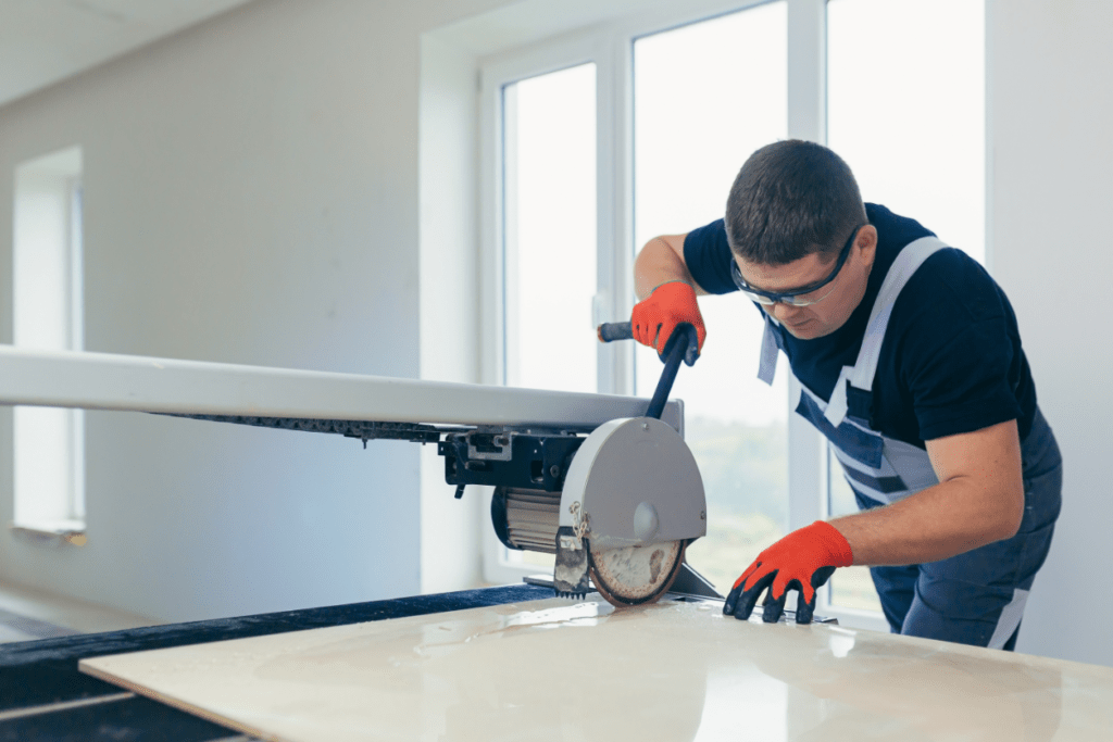 A man using a tile saw to renovate a vanity in a room.