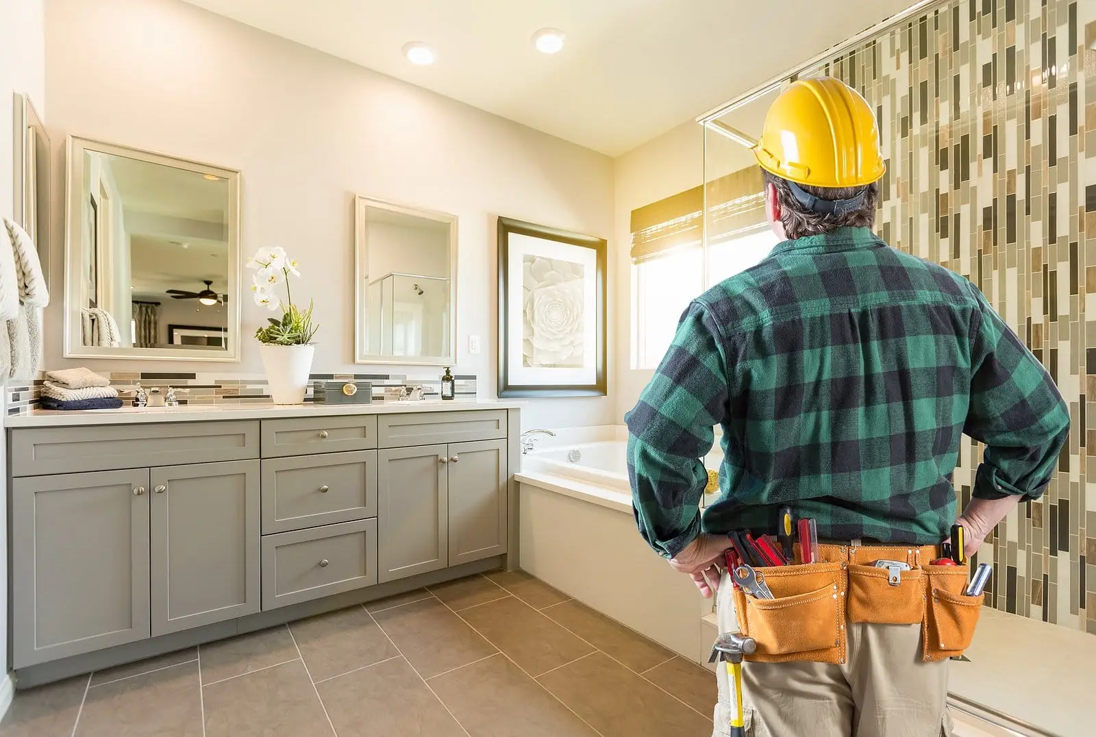 A man wearing a hard hat stands in a bathroom, inspecting the space—expert tips on how to find the right contractor for Toronto bathroom renovations.
