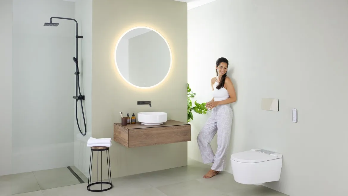 A woman stands at a bathroom sink, engaged in her morning routine, with toiletries neatly arranged around her.