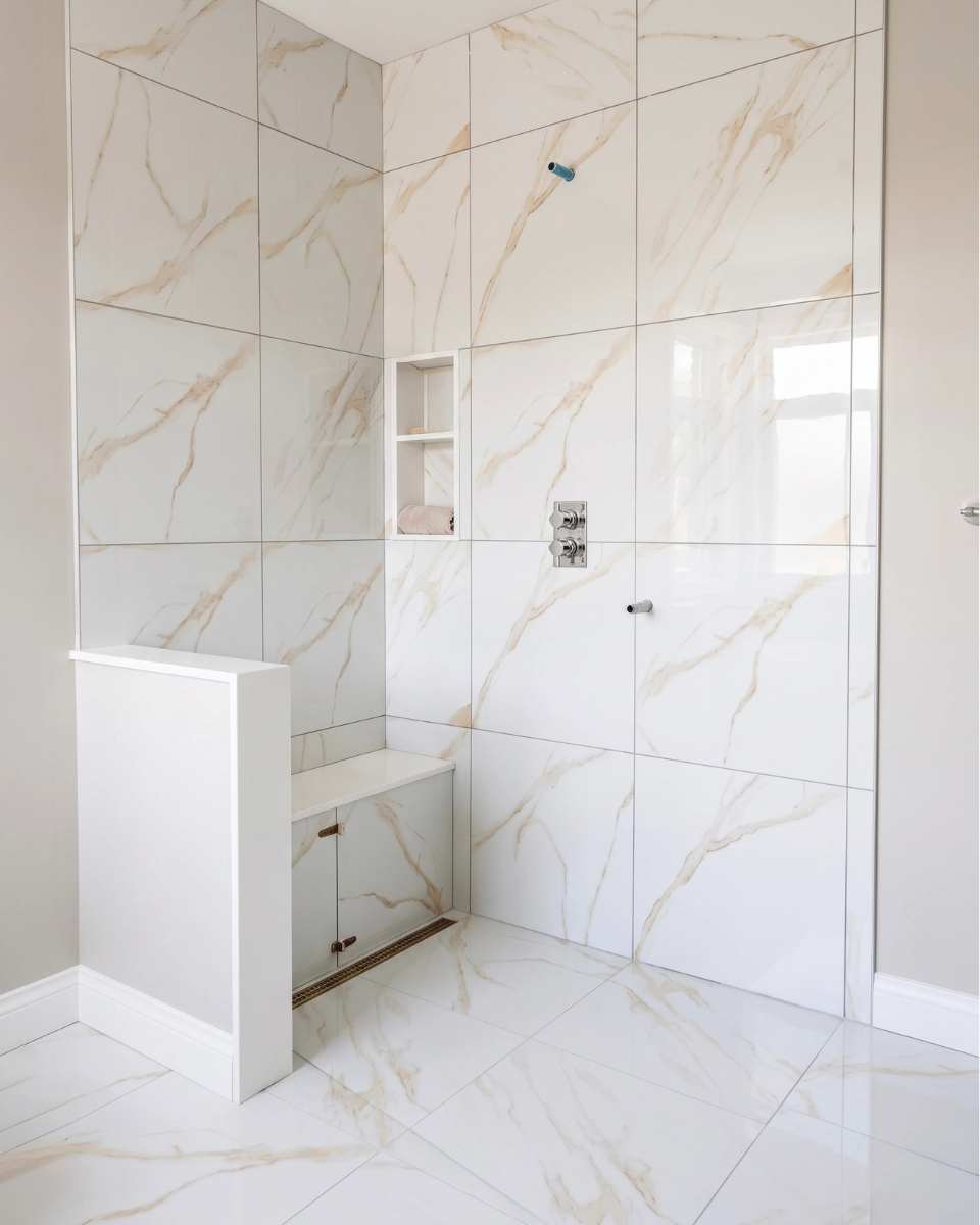 Curbless walk-in shower with a built-in tile bench and frameless glass enclosure in a Burlington bathroom renovation